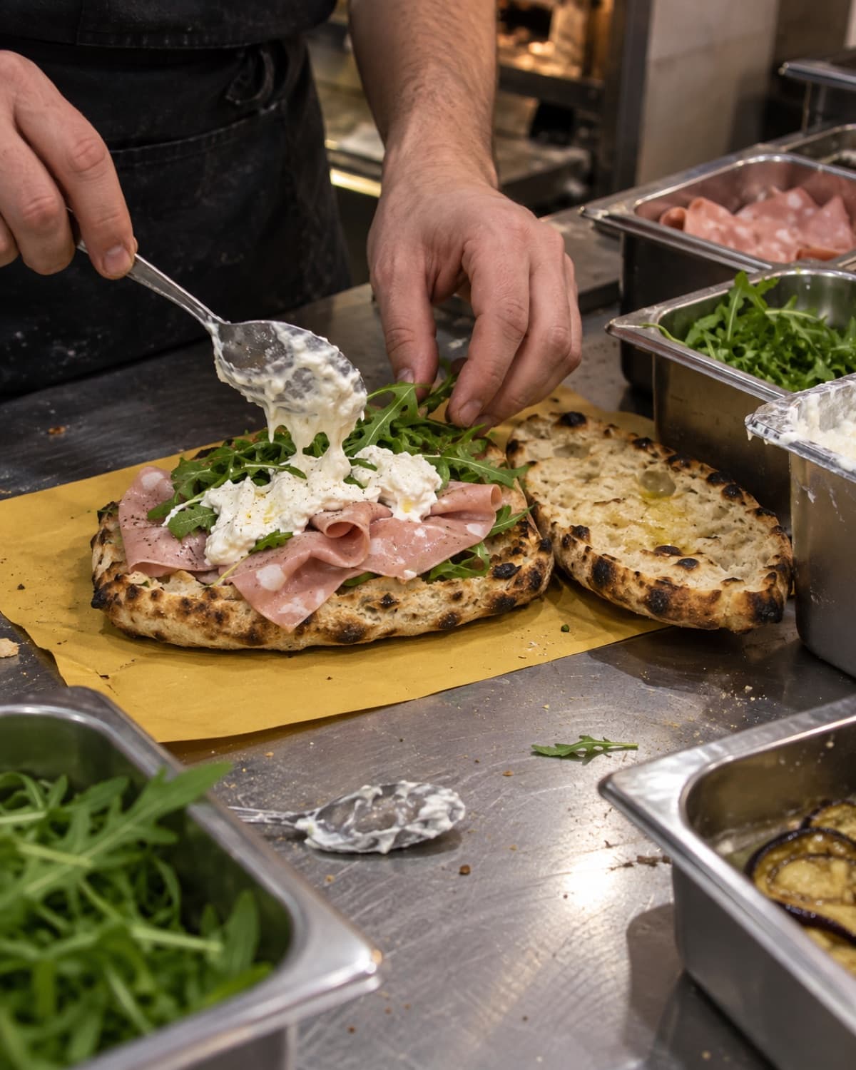 Un pizzaiolo garnit un panuozzo de bufala et de jambon